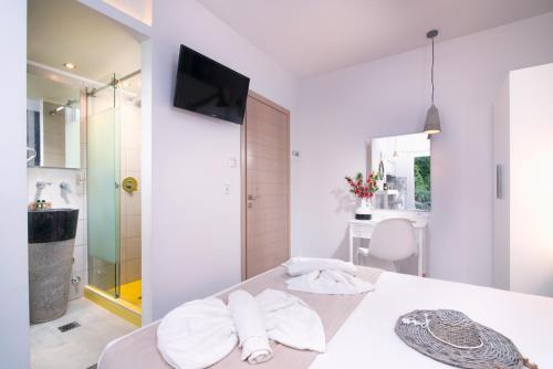 a white bathroom with two towels on a table at Estian Deluxe in Limenaria