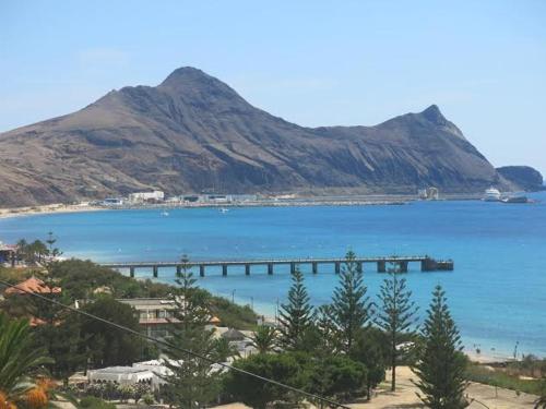 a large body of water with a pier and a mountain at 16 Porto Santo Apartments in Porto Santo