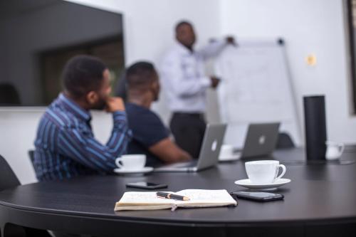 a group of men sitting at a table with a laptop at Nordic Villa in Abuja