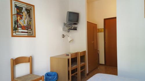 Habitación con TV en la pared, mesa y sillas. en Hotel Firenze, en Malcesine