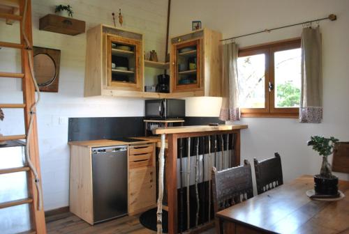 una cucina con armadi in legno, tavolo e frigorifero di L'Etournelle - Cabane Perchée a Chaussan