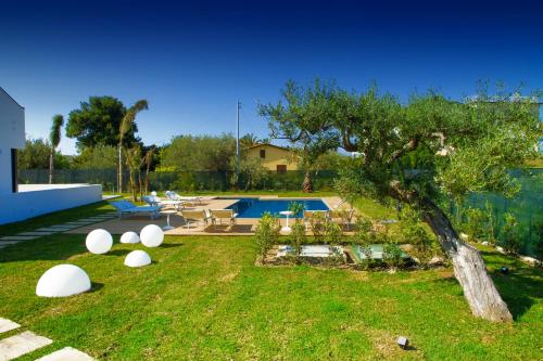 a yard with a pool and lawn furniture at Baia degli Ulivi Apartments in Cefalù
