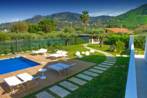 a backyard with a pool and a patio with tables and chairs at Baia degli Ulivi Apartments in Cefalù
