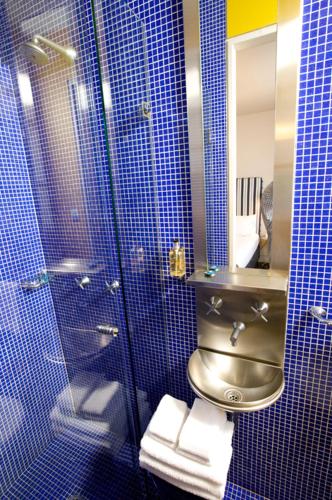a blue tiled bathroom with a toilet and a shower at Dive Hotel in Sydney