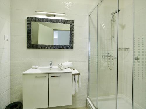 a white bathroom with a sink and a shower at Stars of Zagreb Apartments in Zagreb