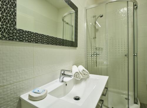 a white bathroom with a sink and a shower at Stars of Zagreb Apartments in Zagreb