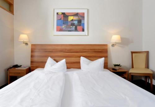 a hotel room with a white bed with two pillows at Hotel Bayerisch Meran in Bad Feilnbach