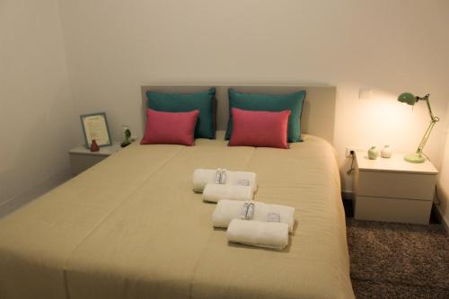 a bedroom with a large bed with pink and green pillows at Charme e Alegria in Viseu
