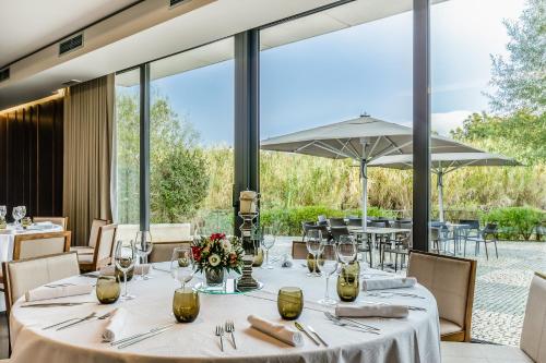 a dining room with tables and chairs and large windows at Hotel Villa Batalha in Batalha