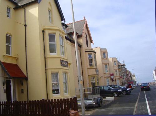 a row of buildings on a city street with cars parked at Tuxford House in Blackpool