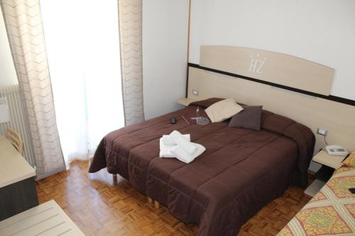 a bedroom with a brown bed with two tissues on it at Hotel Allo Zodiaco in Andalo