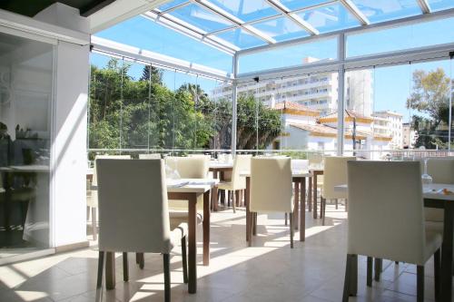 a dining room with windows and tables and chairs at Hotel Años 50 in Torremolinos