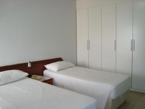 a bedroom with two beds and white cabinets at ABC Apart Hotel in Brasilia