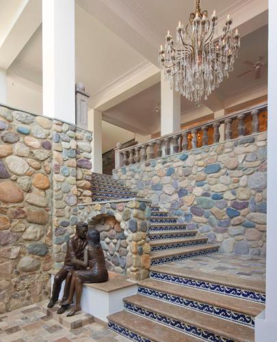 a statue of two women sitting on a bench next to a stone wall at Casa Kimberly Boutique Hotel in Puerto Vallarta