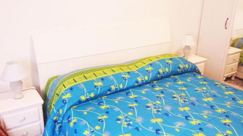 un letto con piumone blu e fiori gialli di Edolo Apartment a Milano