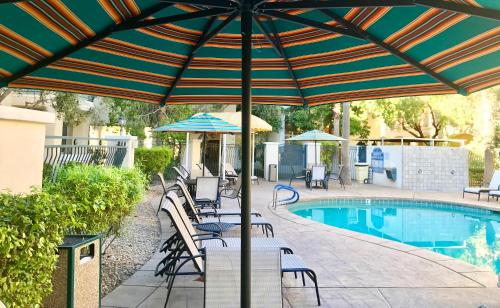un patio con sillas y una sombrilla junto a la piscina en Club de Soleil All-Suite Resort, en Las Vegas