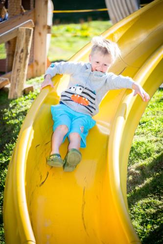 a young boy sliding down a slide on a playground at Almhof-Reithof Pitztal in Sankt Leonhard im Pitztal