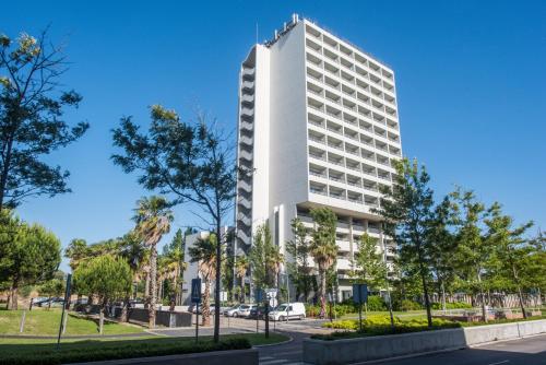 a white building with trees in front of a street at The Editory By The Sea Troia Comporta Hotel in Troia