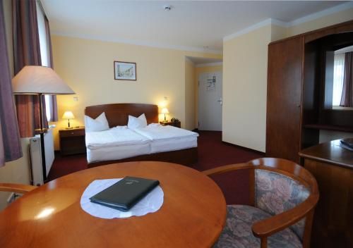 ein Hotelzimmer mit einem Bett und einem Tisch mit einem Laptop darauf in der Unterkunft Hotel Döbelner Hof in Döbeln