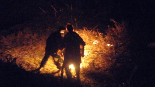 two people walking around a fire at night at Dhanaulti Camp Homes Retreat in Dhanaulti