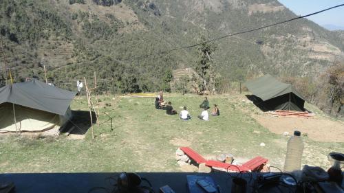 a group of people sitting in a field with tents at Dhanaulti Camp Homes Retreat in Dhanaulti