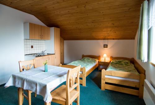 a room with two beds and a table and a kitchen at Pension Pek in Kubova Huť