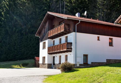 a white building with a balcony on top of it at Pension Pek in Kubova Huť