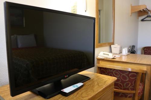 a desk with a television and a computer on it at Highland Country Inn Flagstaff in Flagstaff