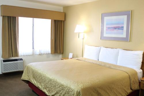 a hotel room with a large bed with white pillows at Highland Country Inn Flagstaff in Flagstaff