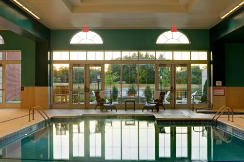 a swimming pool with chairs and a table and windows at Saratoga Casino Hotel in Saratoga Springs