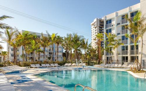 a swimming pool in front of a building with palm trees at Plunge Beach Resort in Fort Lauderdale
