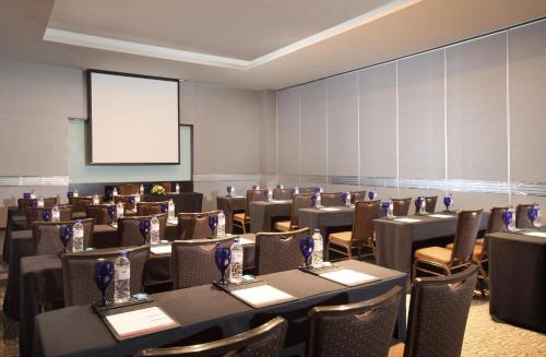 a conference room with tables and chairs and a screen at PO Hotel Semarang in Semarang