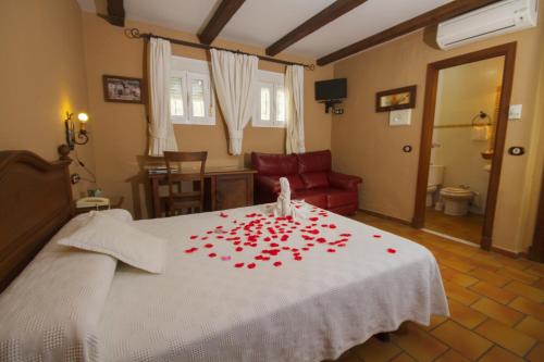 a bedroom with a white bed with red roses on it at Hotel El Tabanco in El Bosque