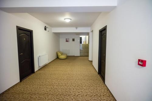 a hallway with two black doors and a yellow chair at Hotel-Restaurant Ayan Piatra Neamt in Piatra Neamţ