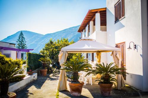 un patio con ombrellone e piante di fronte a un edificio di Casa Papiro a Città di Lipari