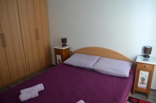een slaapkamer met een groot bed en een paarse deken bij Apartments Nina in Baška