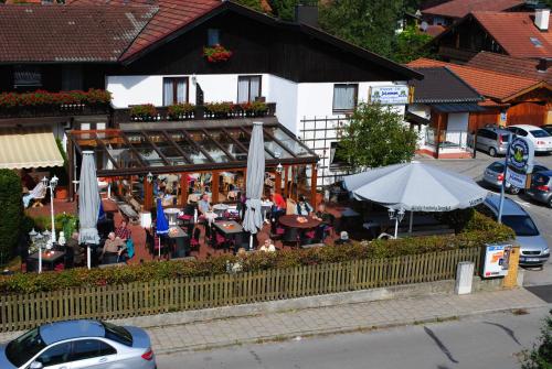 a restaurant with people sitting at tables and an umbrella at Hotel Gasthof Momm in Brunnthal