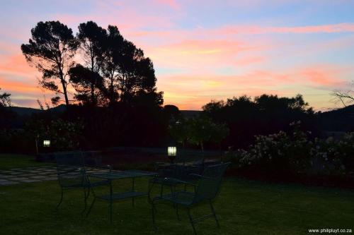 a group of chairs sitting around a table at sunset at Olive Hill Country Lodge in Bloemfontein