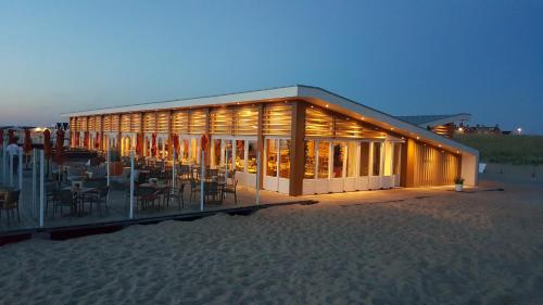 a building on the beach with tables and chairs at Kusthuisjes in Katwijk