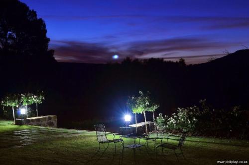 a table and chairs in a field at night at Olive Hill Country Lodge in Bloemfontein