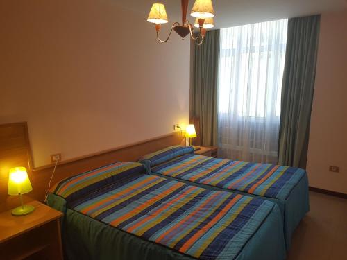 a bedroom with a bed and two lamps and a window at Casa Poy in Becerreá