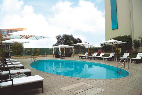 a swimming pool with chairs and umbrellas next to a building at Delfines Hotel & Convention Center in Lima