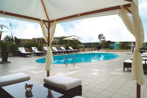 uma piscina com um guarda-sol e cadeiras e uma mesa em Delfines Hotel & Convention Center em Lima