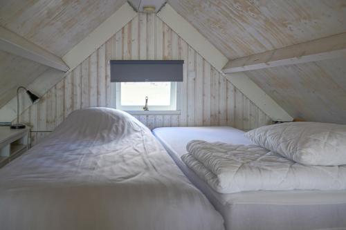 una camera da letto con due letti bianchi in mansarda di Kusthuisjes.nl a Katwijk