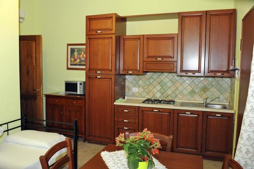 a kitchen with wooden cabinets and a table with flowers at La Fontana Dei Desideri in Alghero