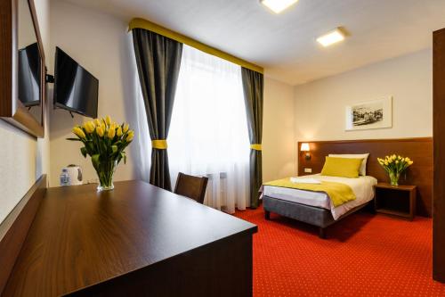 a hotel room with a bed and a desk with flowers at L26 Łopuszańska in Warsaw