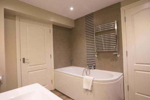 a white bathroom with a tub and a sink at Stirrups Hotel in Bracknell