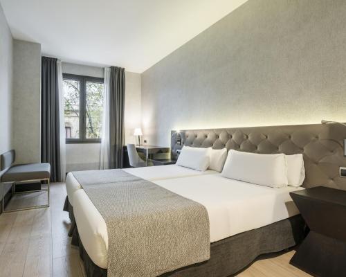 um quarto de hotel com uma cama grande e uma janela em Ilunion Bel-Art em Barcelona