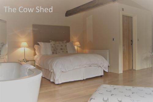 a white bedroom with a bed and a bath tub at The Coach House Denton in Grantham
