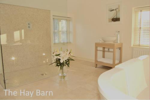 een badkamer met een douche en een vaas met bloemen bij The Coach House Denton in Grantham